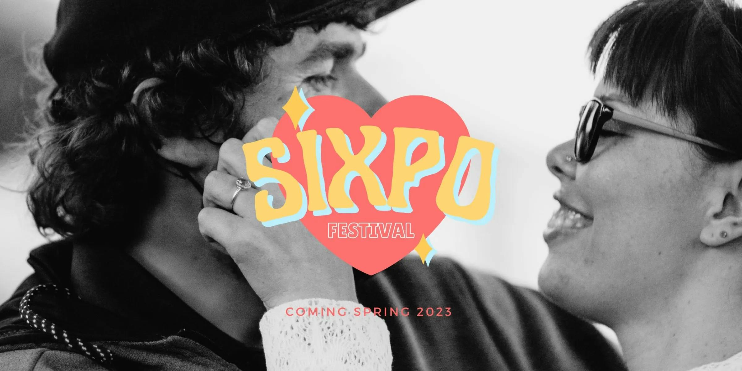A black and white photo of a smiling woman caressing her fiance's face. the SIXpo logo stands in vibrant colors in the center foreground with the words `Coming Spring 2023` printed underneath.